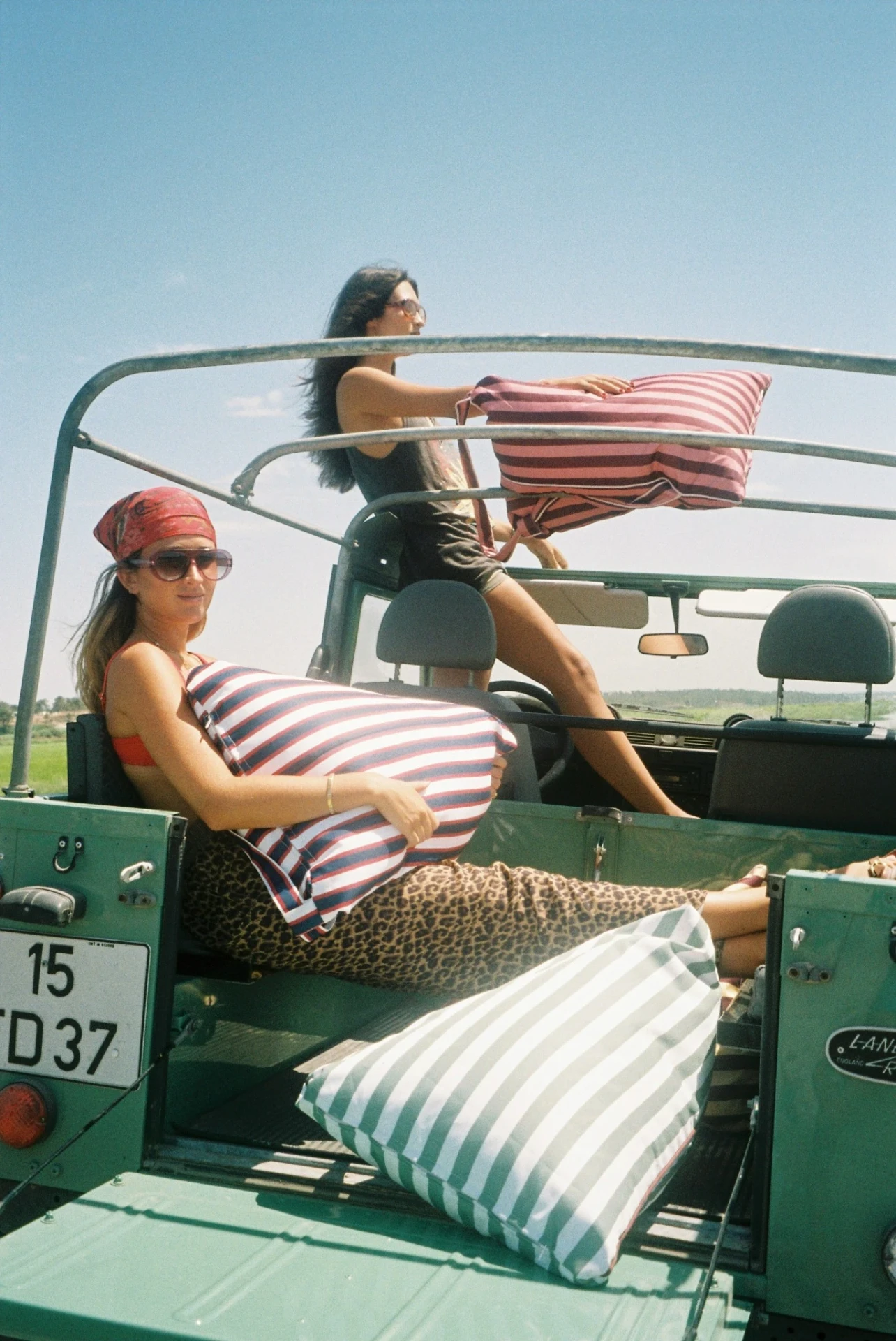 Two friends in a green Land Rover with pink and blue striped LIELOW bags