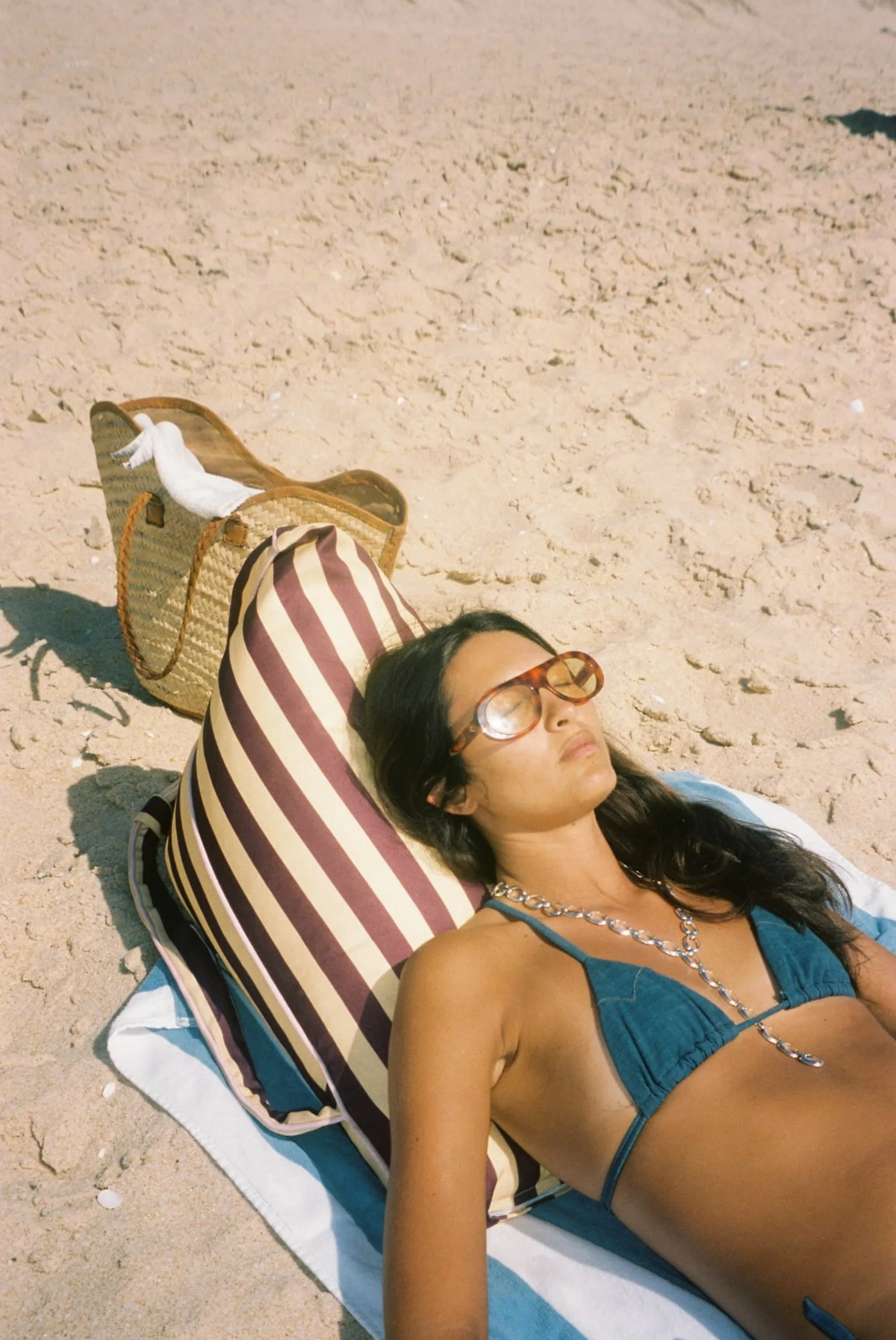 A woman leaning back on a striped LIELOW backrest at the beach
