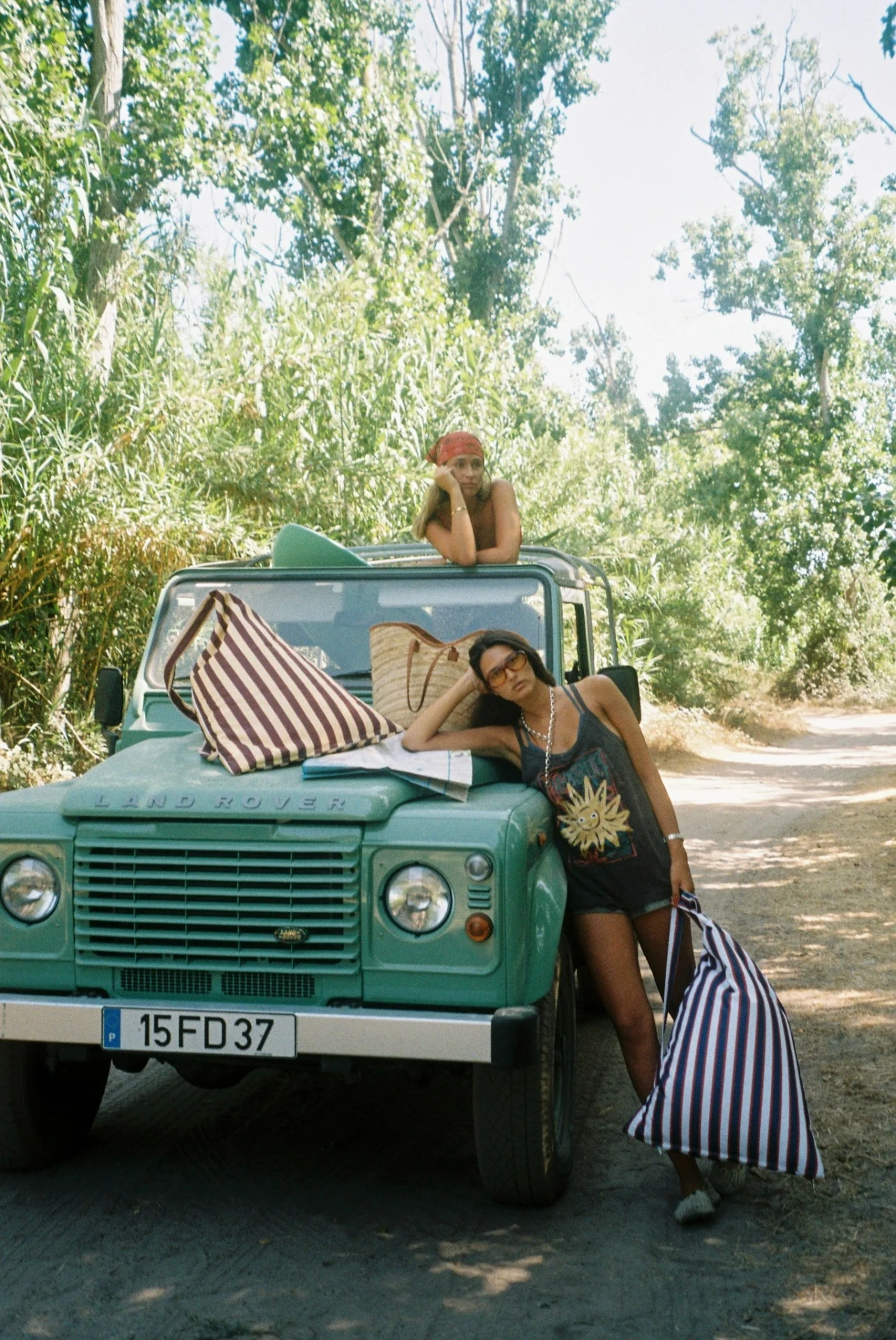 Model leaning on a Land Rover holding a striped LIELOW bag